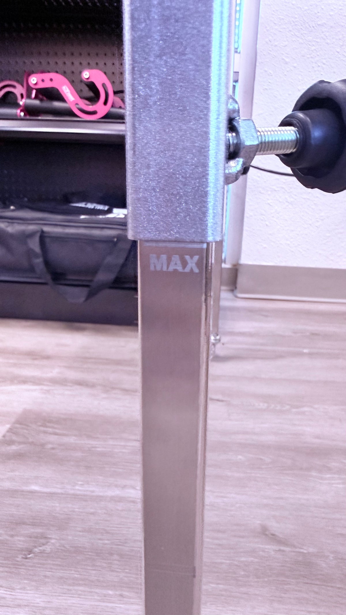 Close-up of a metal barbell with pink weight plates on a wooden floor.
